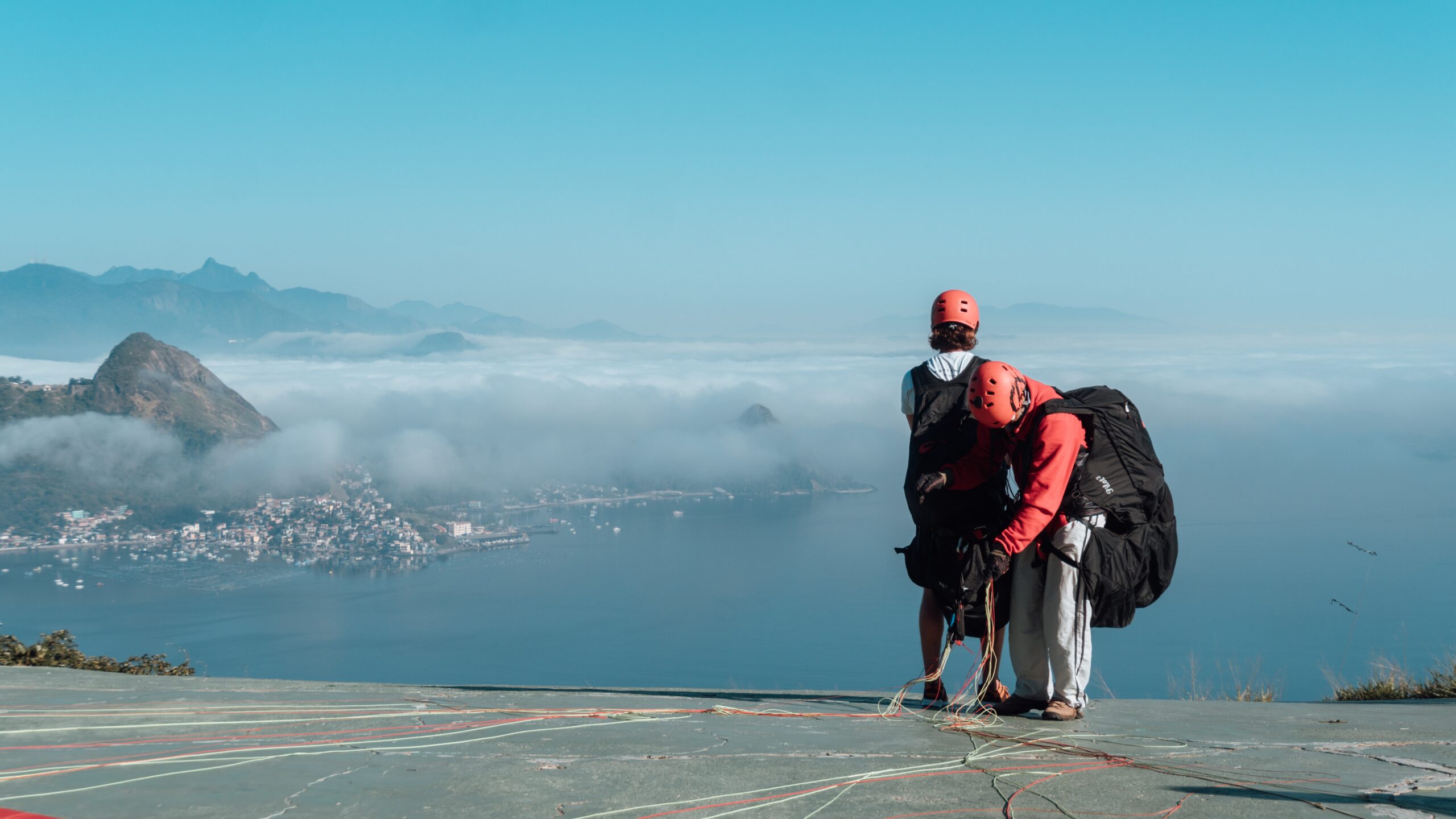 people getting ready to sky glide in rio de janeiro under the beautiful blue sky